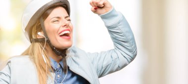 Büyük başarı, güç, enerji ve olumlu duygular ifade Bisiklet kask ve kulaklık mutlu ve heyecanlı kutluyor zafer olan kadın. Yeni iş neşeli kutluyor