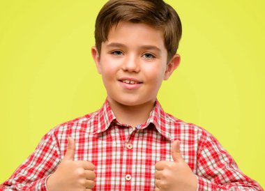 Sarı arka plan üzerinde hareket kamera, gibi ifade ve onay için genel olarak gösterilen gülümseyen yeşil gözlü yakışıklı yürümeye başlayan çocuk yaşasın