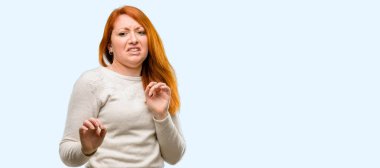 Güzel genç Kızıl saçlı kadın tiksinti ve kızgın, dur jest, bir savunma olarak ellerini tutarak bağırarak mavi arka plan üzerinde izole