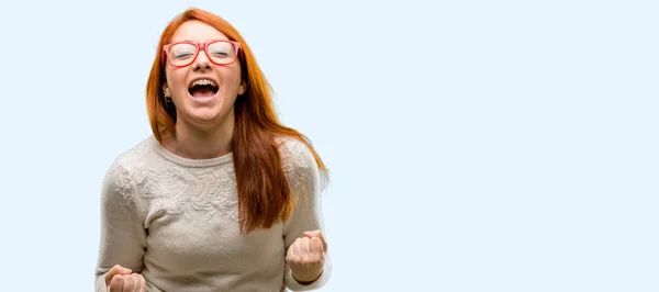 美しい若い赤毛の女性幸せと興奮祝う勝利大成功 エネルギーおよび肯定的な感情を表現します 新しい仕事のうれしそうな青い背景に分離を祝う — ストック写真