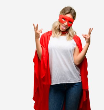 Genç kamera gösteren tong seyir ve parmakları ile işaret zafer yapma pelerin giyen kahraman kadın süper