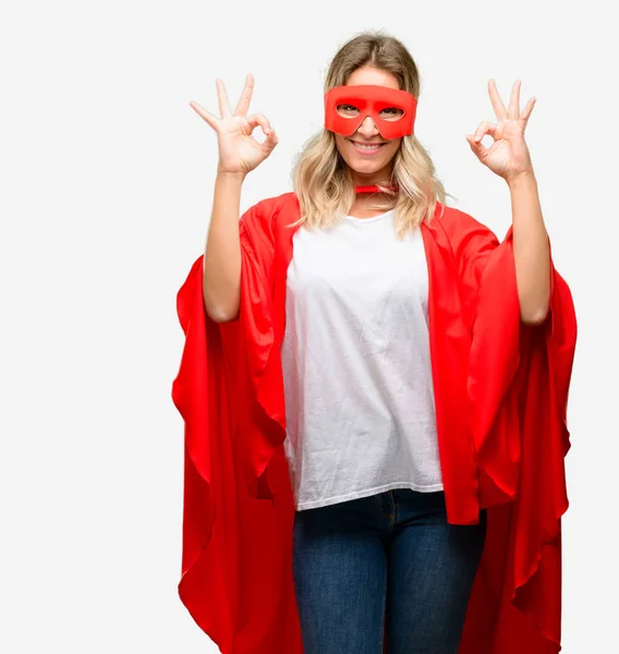 Young super hero woman wearing cape doing ok sign gesture with both hands expressing meditation and relaxation