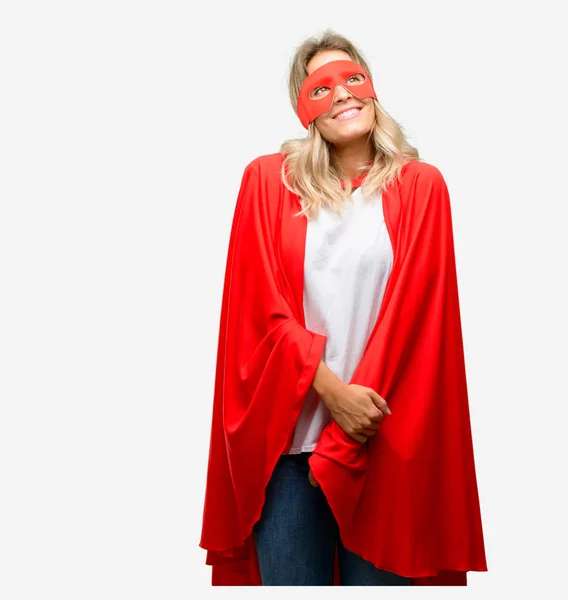 Young super hero woman wearing cape thinking and looking up expressing doubt and wonder