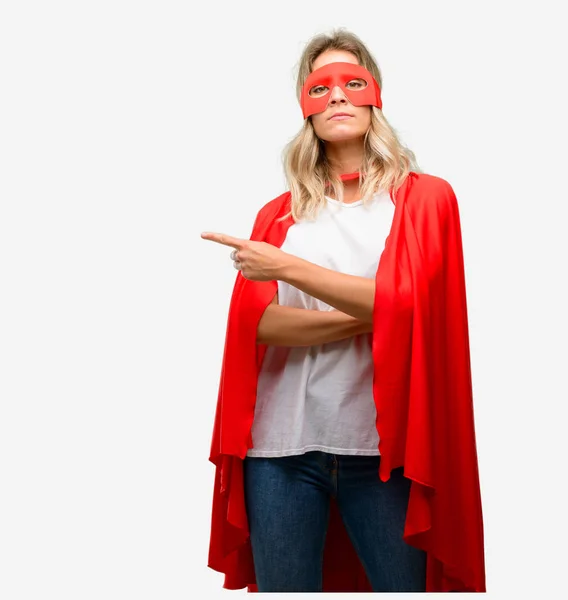 Young super hero woman wearing cape pointing away side with finger
