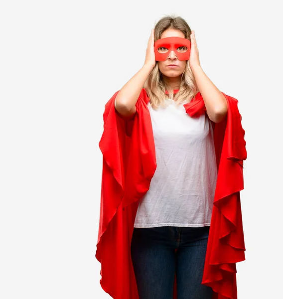 Young super hero woman wearing cape covering ears ignoring annoying loud noise, plugs ears to avoid hearing sound. Noisy music is a problem.