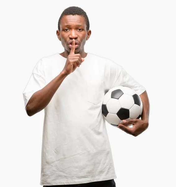 アフリカ黒人静かに求める唇に 人差し指でサッカー ボールを保持しています 沈黙と秘密の概念 — ストック写真