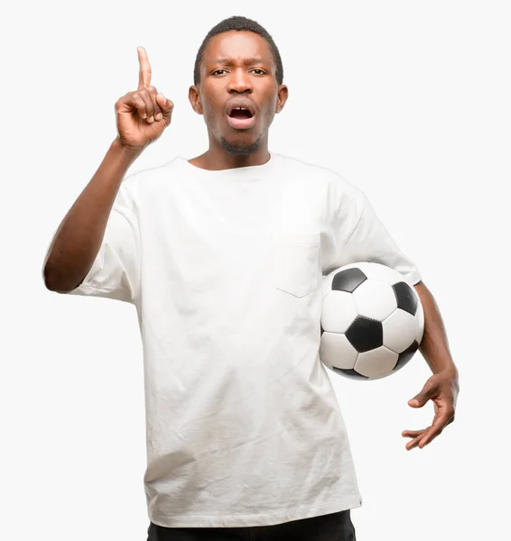 指でアウェイ側を指しているサッカー ボールを保持しているアフリカの黒人男性 — ストック写真
