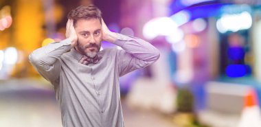 Orta yaş adam, sakal ve papyon kulakları rahatsız edici gürültü, görmezden kapsayan kulak işitme ses önlemek için fişler. Gürültülü müzik bir sorundur. gece kulübünde