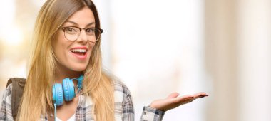 Genç öğrenci ve kadın ile kulaklıklar bir şey boş elinde tutan sırt çantası