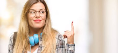 Genç öğrenci kadın parmağını, bir numara yükselterek sırt çantası ve kulaklık ile