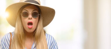 Panik ve korku ifade şokta, güneş gözlüğü ve yaz şapka giyen genç kadın korkuttu