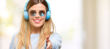 Genç kadın müzik dinlemek için kulaklık tutar ile eller el sıkışma poz, konuksever güven ve başarı kavramı ifade, tebrik