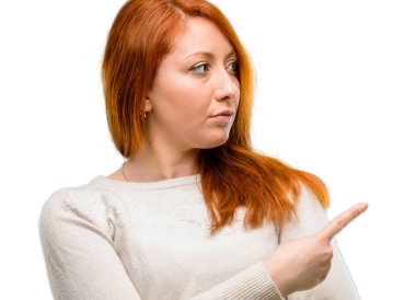 Uzak yan beyaz arka plan üzerinde izole parmak ile işaret eden güzel genç Kızıl saçlı kadın