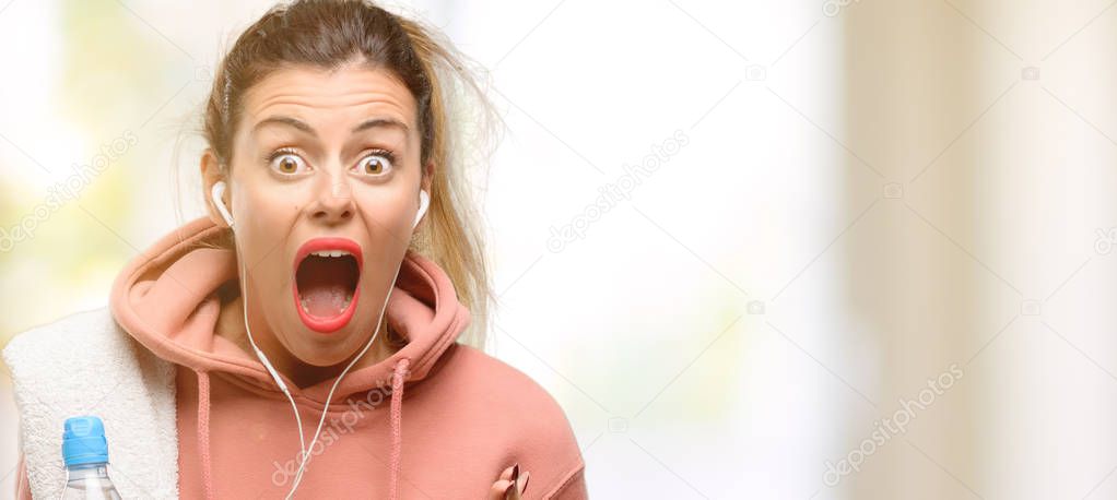 Young sport woman wearing workout sweatshirt stressful keeping hands on head, terrified in panic, shouting