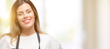 Kendinden emin ve mutlu bir büyük doğal gülümseme gülmek ile önlük giyen dükkanı sahibi kadın