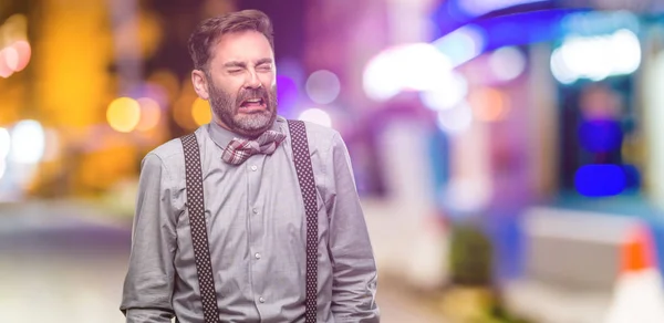 Middle age man, with beard and bow tie crying depressed full of sadness expressing sad emotion at night club