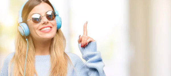 年轻妇女听音乐与耳机举起手指 第一个 — 图库照片