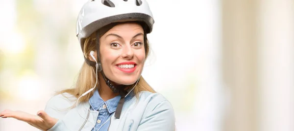 年轻妇女用自行车头盔和耳机拿着东西在空的手 — 图库照片