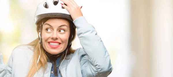 骑自行车头盔和耳机的年轻妇女用手指指着一边 — 图库照片