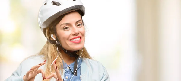 自転車用ヘルメットとイヤホンと愛を示す幸せな若い女性の健康を表現するハートの形で結婚のシンボル手します — ストック写真