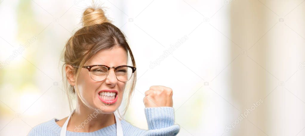 Young woman shop owner, wearing apron irritated and angry expressing negative emotion, annoyed with someone