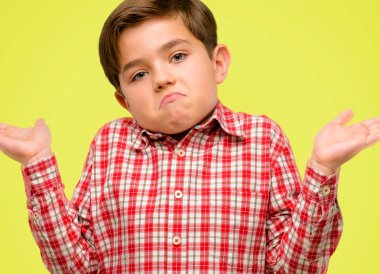 Yeşil gözlü yakışıklı yürümeye başlayan çocuk ifade şüphe, şaşırtmak ve kavramı, sarı arka plan üzerinde belirsiz gelecek merak ediyorum