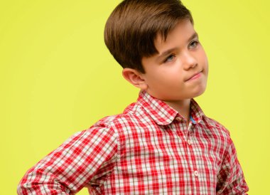 Kendinden emin ve mutlu sarı arka plan üzerinde gülüyor büyük bir doğal gülümseme ile yeşil gözlü yakışıklı yürümeye başlayan çocuk