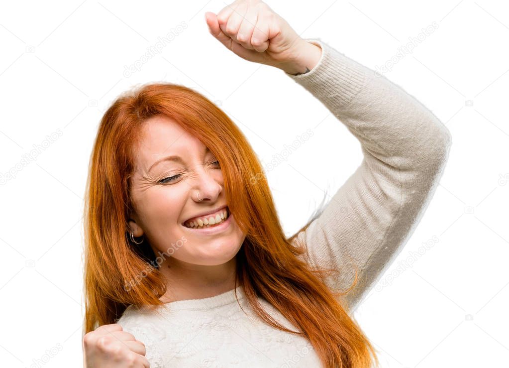 Beautiful young redhead woman happy and excited expressing winning gesture. Successful and celebrating victory, triumphant isolated over white background