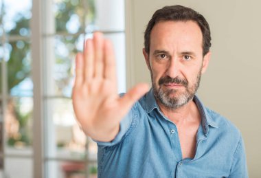 Yakışıklı orta yaş erkek açık eliyle dur işareti ile ciddi ve kendine güvenen ifade, savunma hareketi yapıyor