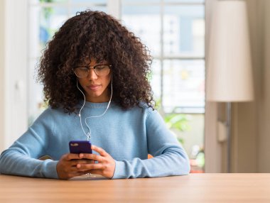 Acımak yüz ciddi düşünüyorum üstünde kendine güvenen bir ifade ile akıllı telefon kullanan güzel Afrikalı-Amerikalı kadın