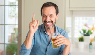 Orta yaş erkek bir fikirle sürpriz bira içmek ya da gülen yüz, bir numara ile işaret parmağı soru