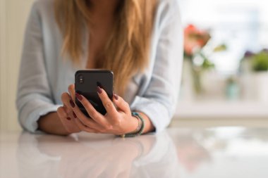 Evde akıllı telefon kullanan bir kadın.