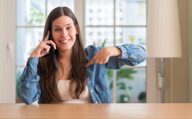 Kendisi için sürpriz yüz işaret parmağı ile akıllı telefon kullanan genç kadın