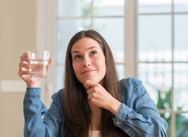 ホームの深刻な顔を考えて質問に非常に水のガラスを飲む若い女性に考えが混乱しています — ストック写真