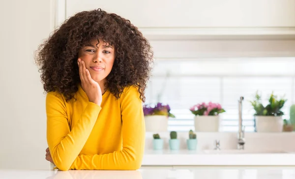 在厨房里穿着黄色毛衣的非洲裔美国妇女 手里带着痛苦的表情 因为牙痛或牙齿疾病 牙医概念 — 图库照片
