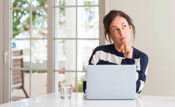 Mulher Meia Idade Usando Laptop Casa Rosto Sério Pensando Questão — Fotografia de Stock
