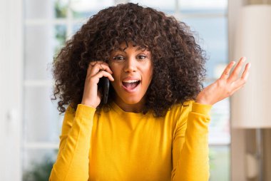 Afrikalı-Amerikalı kadın büyük gülümseme ile çığlık zaferini kutluyor ve ellerini kaldırdı smartphone çok mutlu ve heyecanlı, kazanan ifade kullanma
