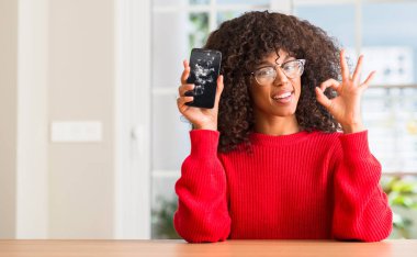 Kırık smartphone parmak, mükemmel sembolü ile ok işareti yapıyor tutan Afrikalı-Amerikalı kadın