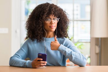 Ok işareti, başparmak ile parmak, mükemmel işareti yapıyor kocaman bir gülümseme ile Smartphone mutlu kullanan güzel Afrikalı-Amerikalı kadın