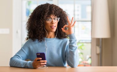 Parmak, mükemmel sembolü ile ok işareti yapıyor smartphone kullanarak güzel bir Afrikalı-Amerikalı kadın