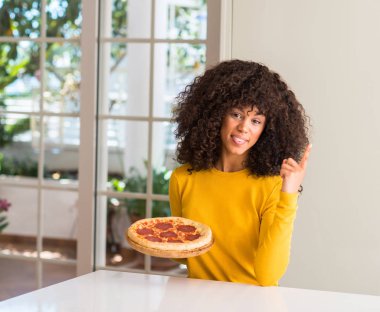 Afrikalı-Amerikalı kadın ev çok mutlu el ve parmak ile tarafına işaret lezzetli biberli pizza yemeye hazır