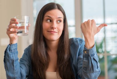 El ve parmak kadar mutlu yüz gülümseyen genç kadın evde bardak su içme işaret