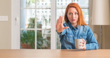 Bir fincan kahve ile tutan Kızıl saçlı kadın dur işareti ile ciddi ve kendine güvenen ifade, savunma hareketi yaparken el açmak