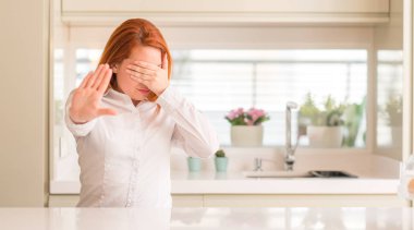 Kızıl saçlı kadına mutfak kapsayan gözlerle eller ve üzgün dur jestle yapıyor ve korku ifadesi. Utandım ve negatif kavramı.