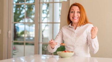 Duygu tezahürat ev gurur çığlık ve kutluyor zafer ve başarı çok heyecanlı, ahududu ile tahıl yemek Kızıl saçlı kadın