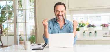 Orta yaş erkek tezahürat duygu heyecan gurur çığlık ve zafer ve başarı çok kutluyor, dizüstü evde kullanma