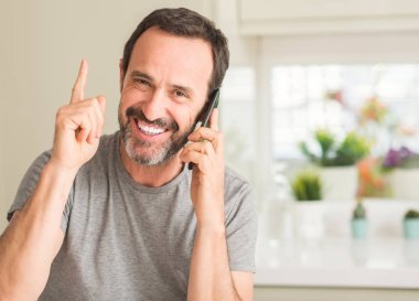 Smartphone sürpriz bir fikirle kullanan yaş adam orta veya gülen yüz, bir numara ile işaret parmağı soru