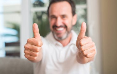 Yakışıklı orta yaş erkek ok işareti, başparmak ile parmak, mükemmel işareti yapıyor kocaman bir gülümseme ile mutlu