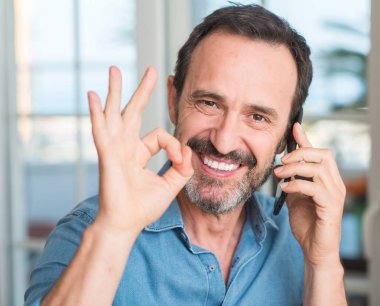 Parmak, mükemmel sembolü ile ok işareti yapıyor smartphone kullanarak orta yaş erkek