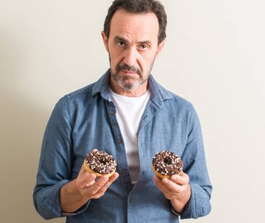 Komuta sizde ciddi düşünme akıllı yüzünde kendinden emin bir ifade ile çikolatalı çörek yeme